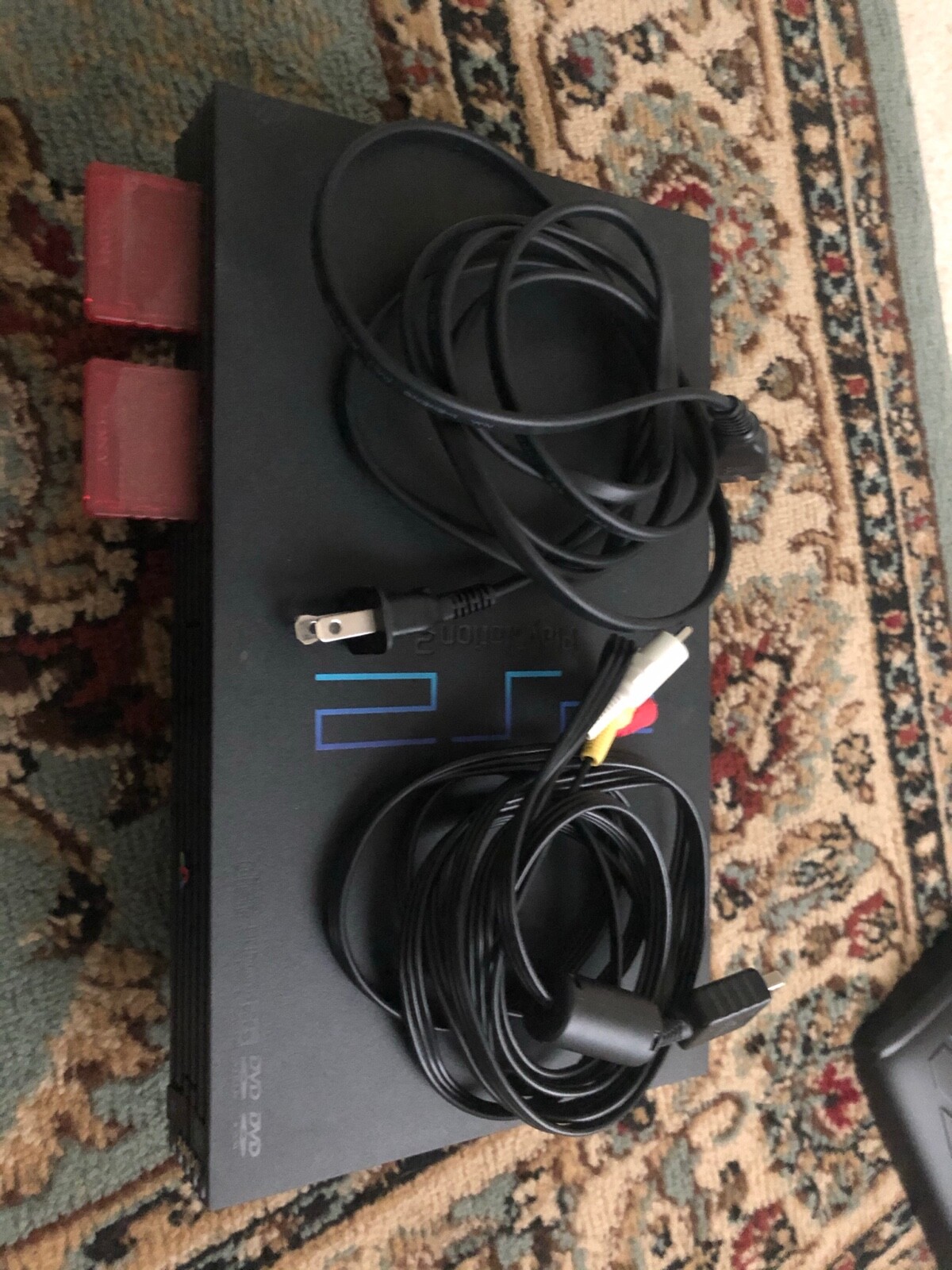 Black Sony PlayStation 2 lot with 2 controllers, 32 MB of memory, and 3 games.