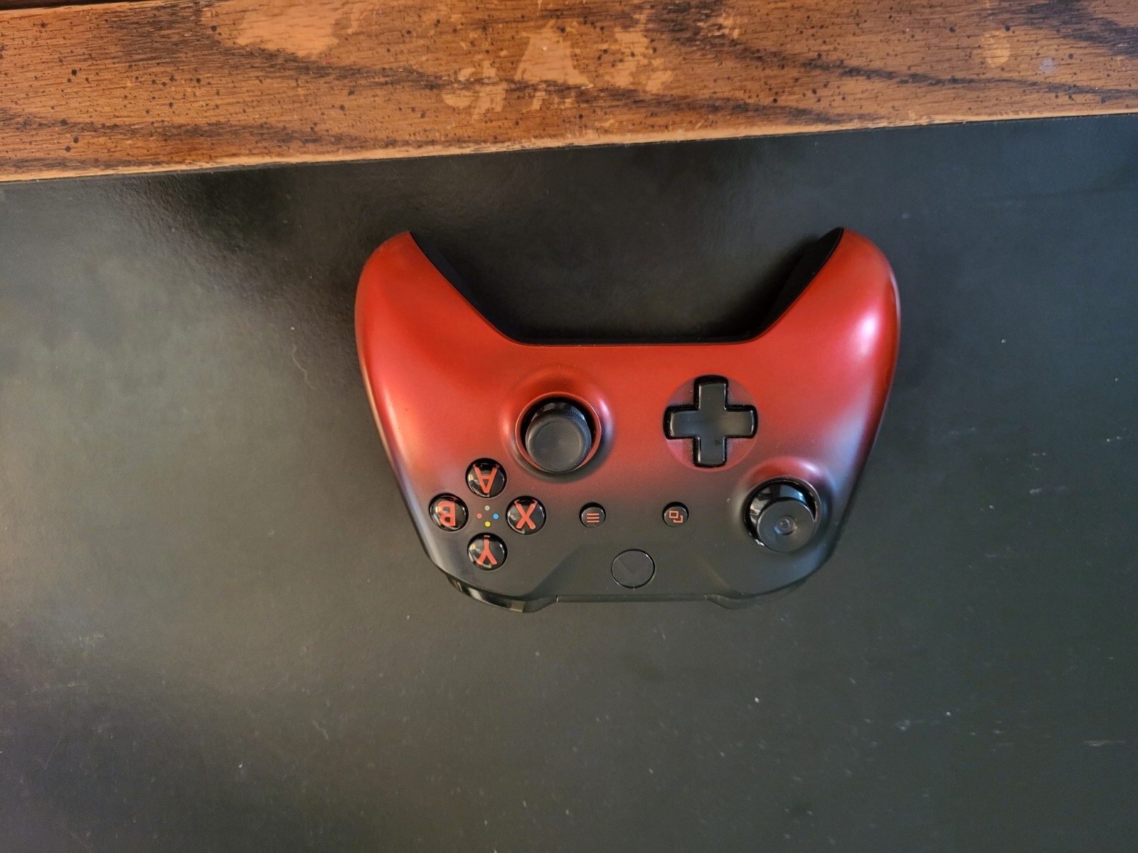 Black Xbox One Console with three wireless remotes.  Turqoise, Red, and White.