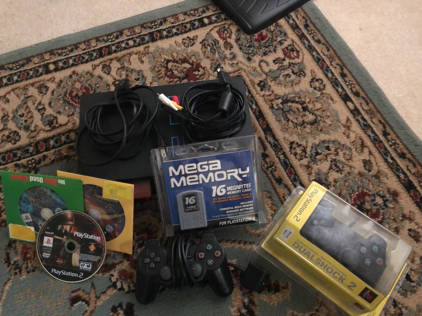 Black Sony PlayStation 2 lot with 2 controllers, 32 MB of memory, and 3 games.